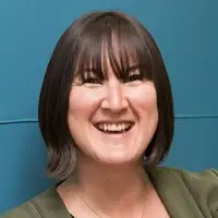Susanna | Apprenticeship and Training Awards | Apprenticeship and Training Awards Smiling woman with short dark hair and bangs, wearing a green top, against a teal background.