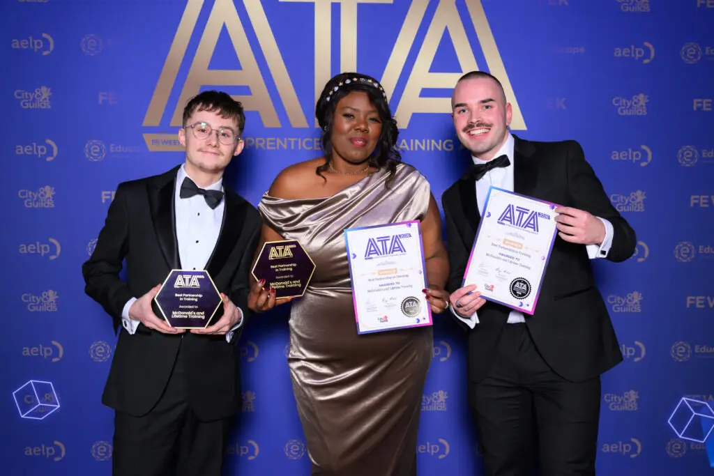 Three winners holding ATA trophies and certificates in front of the Apprenticeship and Training Awards backdrop.