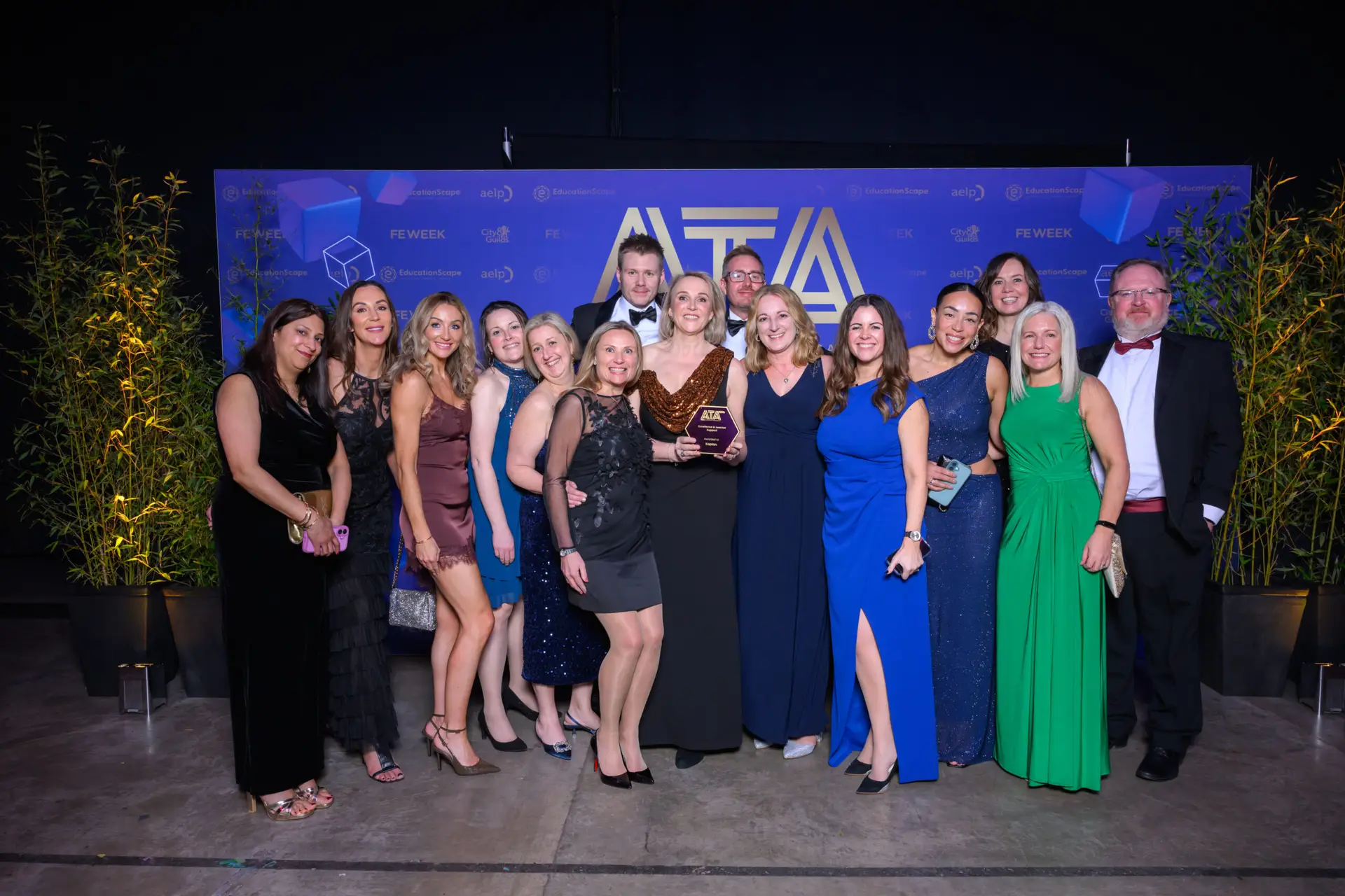 Large group of winners in evening wear in front of the Apprenticeship and Training Awards backdrop.