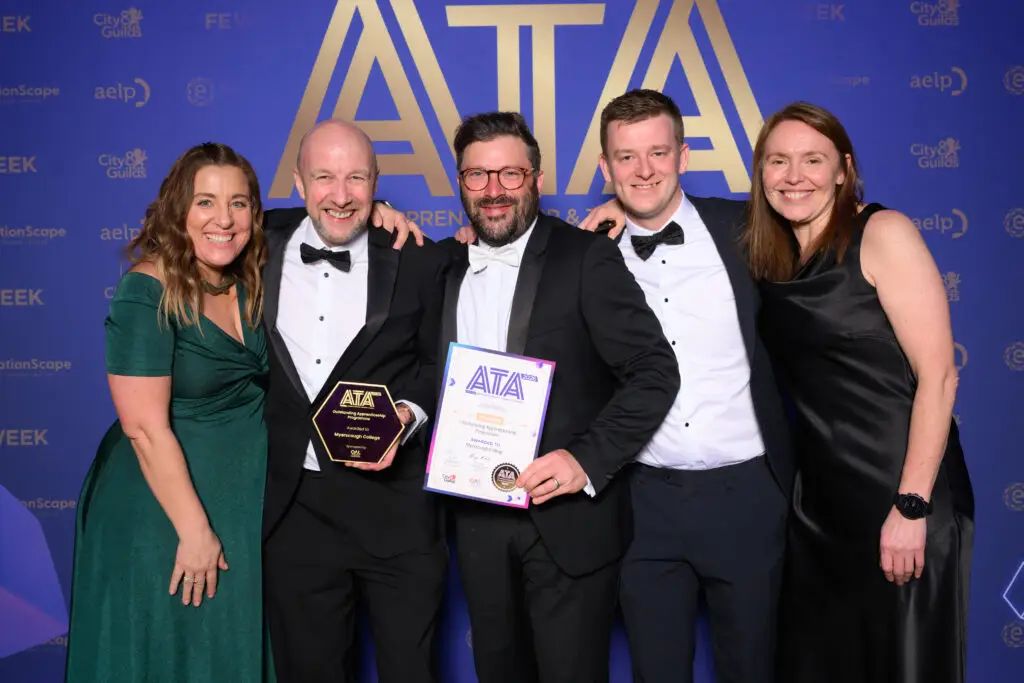 Five winners smiling with their ATA trophy and certificate in front of the awards backdrop.